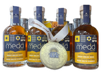 Four bottles of Mountain Mead Whisky Barrel Aged Sweet Welsh Mead with a large gold medal in the foreground, set on a wooden shelf with other bottles blurred in the background.